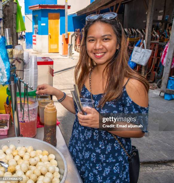the woman try the filipino traditional street food, divisoria, manila, philippines - divisoria manila stock pictures, royalty-free photos & images