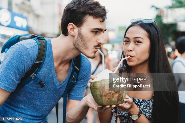 バンコクの市場で一緒にココナッツを飲む若いカップル - 2 coconut drinks ストックフォトと画像