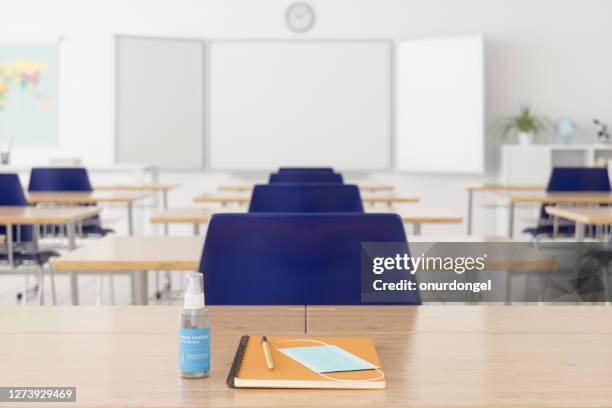 masker, notitieboekje en potlood op het bureau met vaag leeg klaslokaal - social distancing classroom stockfoto's en -beelden