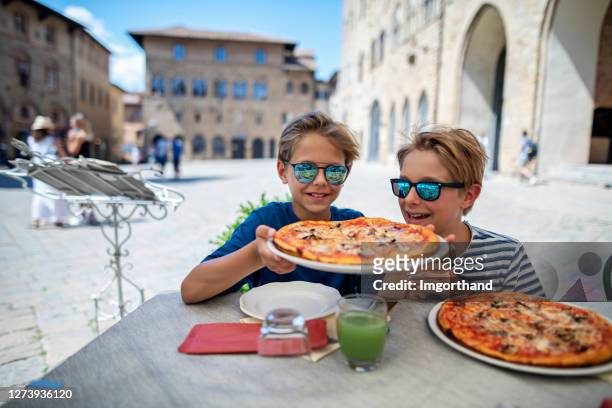little boys enjoying pizza at an italian restaurant - italian family stock pictures, royalty-free photos & images