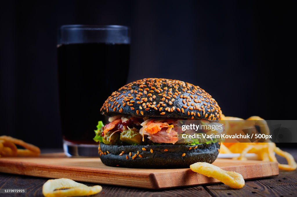 Close-up of burger and french fries on table against black background