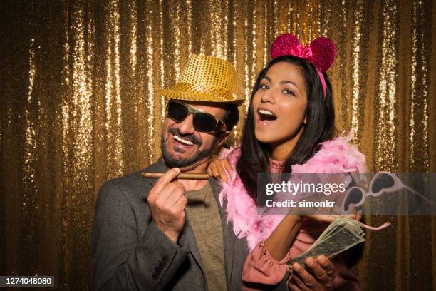 portrait of mature man and young woman enjoying party - gold coat stock pictures, royalty-free photos & images