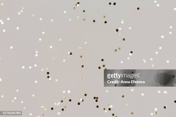 small golden confetti on gray background - glamour stock pictures, royalty-free photos & images