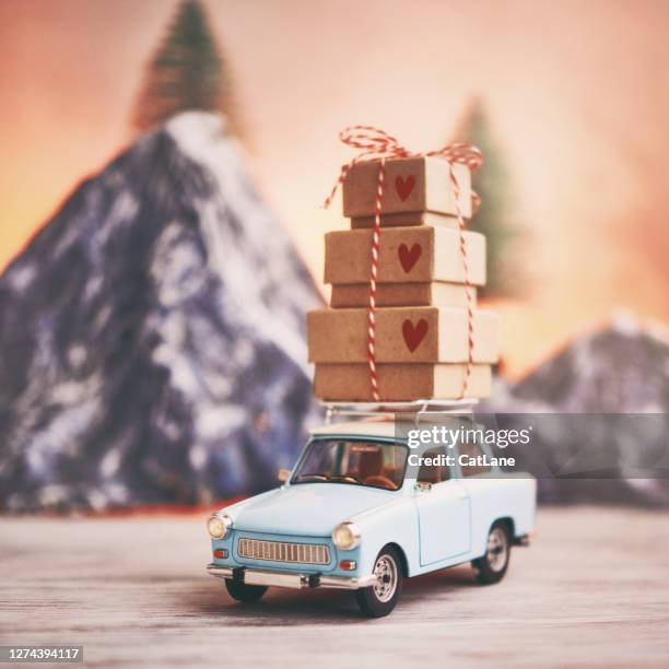 kleines blaues auto mit geschenkstapel auf dachträger vor der bergkette - car roof box stock-fotos und bilder