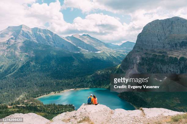 couple sitting on cliff, glacier national park, montana, usa - glacier nationalpark usa bildbanksfoton och bilder