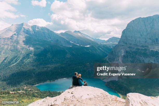 couple sitting on cliff, glacier national park, montana, usa - glacier national park us stock pictures, royalty-free photos & images