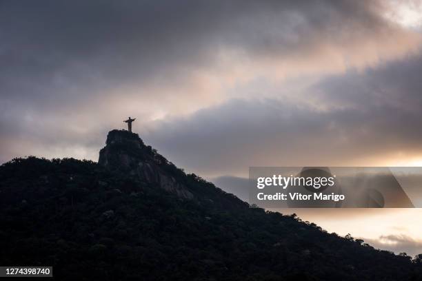 christ the redeemer statue on top of mountain with beautiful sunset clouds in rio de janeiro, brazil - rio de janeiro christ stock pictures, royalty-free photos & images