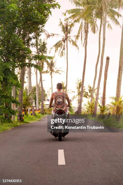 man riding motorcycle along empty highway, bali, indonesia - indonesia bikes traffic stockfoto's en -beelden