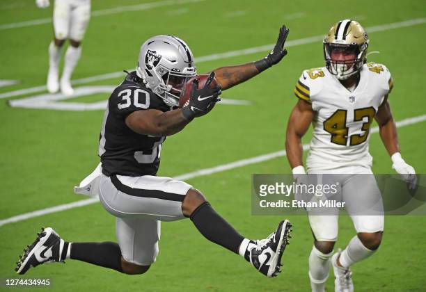 Running back Jalen Richard of the Las Vegas Raiders leaps into the end zone to score a 20-yard rushing touchdown ahead of free safety Marcus Williams...