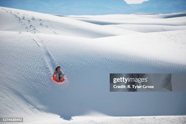 woman sledding down sand dune, white sands national monument, new mexico, usa - white sands national monument stock pictures, royalty-free photos & images