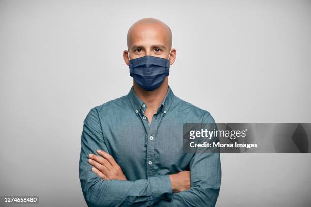smiling businessman with arms crossed wearing home made face mask. - man studio shot stock pictures, royalty-free photos & images