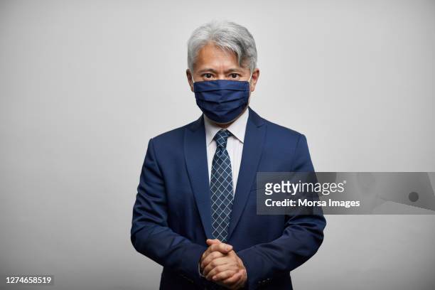 portrait of confident japanese male leader wearing handmade face mask and navy suit - man studio shot stock pictures, royalty-free photos & images