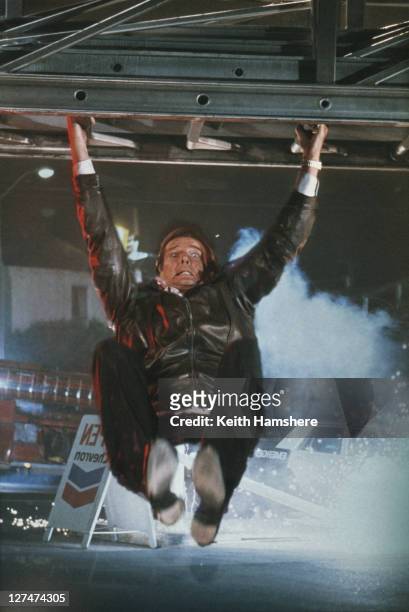 Matte shot of English actor Roger Moore as 007, hanging from a fire engine ladder in a publicity still for the James Bond film 'A View To A Kill',...