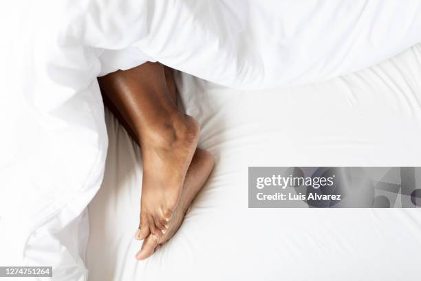 female feet under blanket - feet in bed stock-fotos und bilder