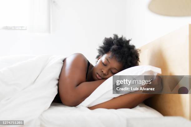 woman sleeping in her bed at home - acostado de lado fotografías e imágenes de stock