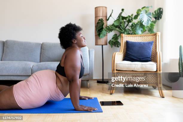 woman doing yoga exercise at home - curvy black women stockfoto's en -beelden