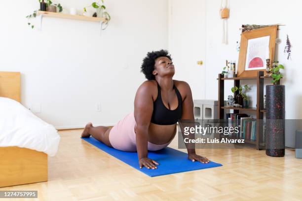 woman doing yoga exercise at home - voluptuous black women stock pictures, royalty-free photos & images