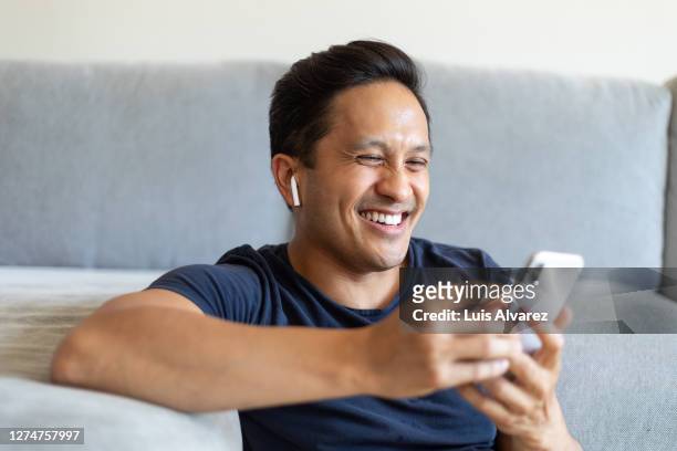 man smiling during a video call on his cell phone at home - navy blue interior stock pictures, royalty-free photos & images