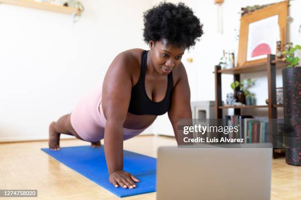 woman exercising at home following a fitness video online - flexiones fotografías e imágenes de stock
