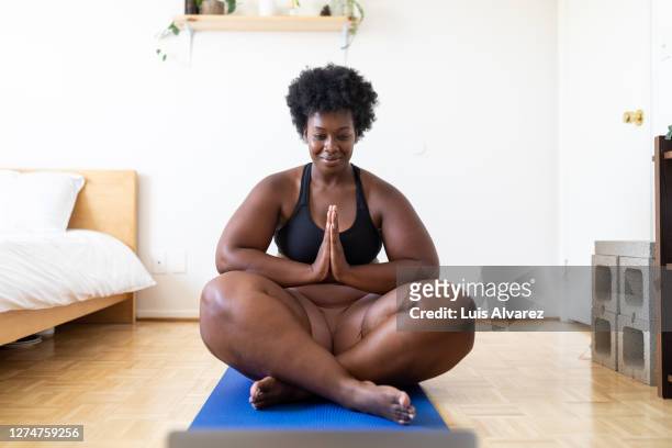 woman doing yoga workout at home - voluptuous black women stockfoto's en -beelden