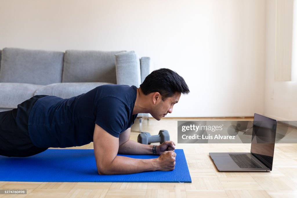 Man doing workout at home watching video tutorial