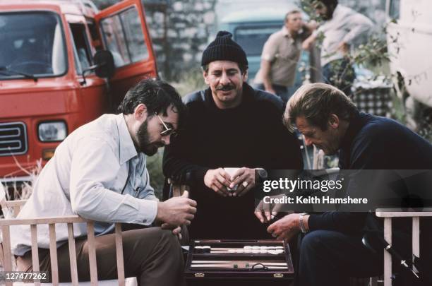 From left to right, producer and screenwriter Michael G. Wilson plays backgammon with Israeli actor Topol and English actor Roger Moore on the set of...