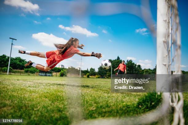 tieners die strafschoppen oefenen en voetballen. vrouwelijke doelman die voetbal met vriend speelt - verdediger voetballer stockfoto's en -beelden