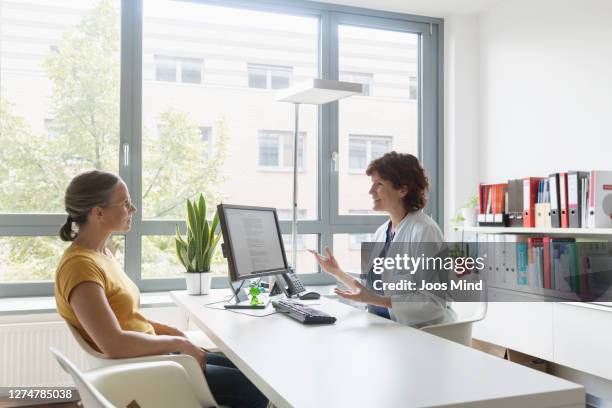 female doctor talking to female patient at doctors surgery - 女性患者 ストックフォトと画像
