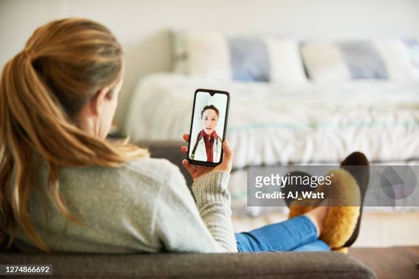 femme utilisant une application de téléphone intelligent pour parler avec son docteur de la maison - femme de dos smartphone photos et images de collection