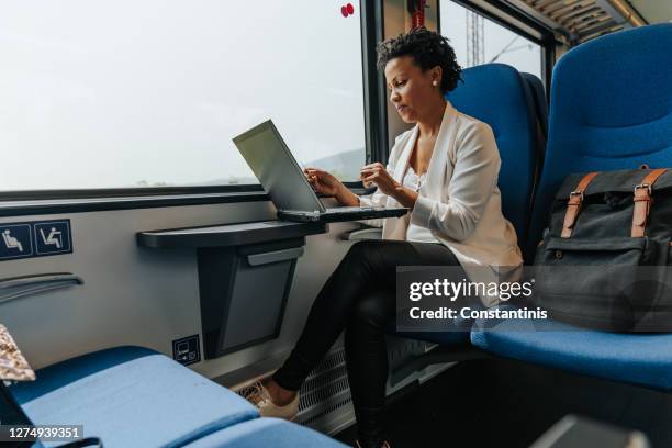 businesswoman using a laptop on the train - businesswear stock pictures, royalty-free photos & images