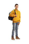 Male teenage student in a yellow hoodie and a backpack smiling at the camera