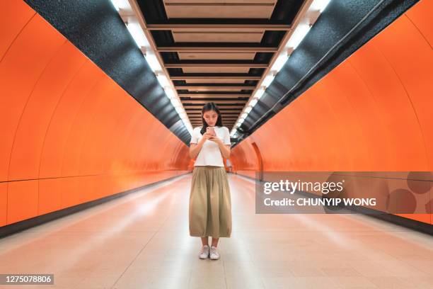 asian woman texting at the metro station - distant people stock pictures, royalty-free photos & images