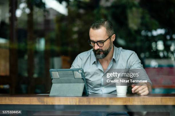 front view of a confidence man working online at a cafe using a digital tablet. portability, flexibility, city life. - coffee shop owner stock pictures, royalty-free photos & images