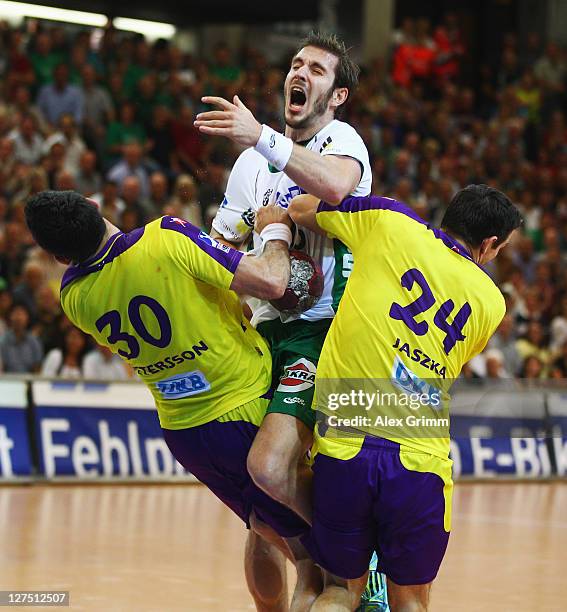 Michael Haass of Goeppingen is challenged by Alexander Petersson and Bartlomiej Jaszka of Berlin during the Toyota Handball Bundesliga match between...