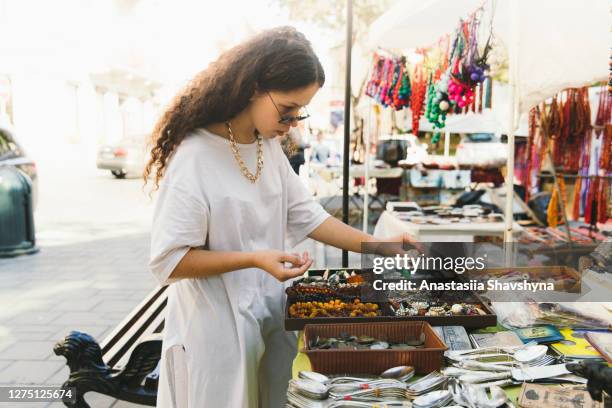 junge frau mit lockigen haaren einkaufen auf flohmarkt an hell sonnigen tag - flohmarkt stock-fotos und bilder