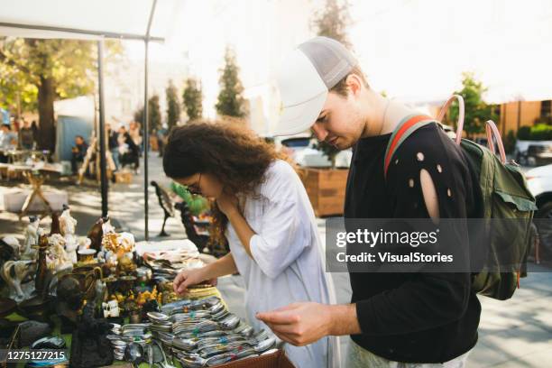 junges paar beim einkaufen auf dem flohmarkt bei strahlendem sonnenschein - flohmarkt stock-fotos und bilder