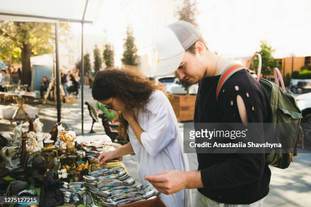 jong paar dat bij de vlooienmarkt tijdens heldere zonnige dag winkelt - flea market stockfoto's en -beelden