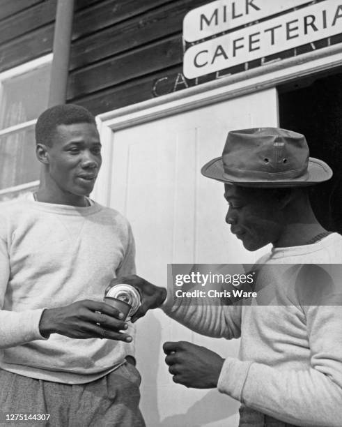Trinidadian athlete Wilfred Tull and Trinidadian weightlifter Rodney Wilkes outside the milk bar at the Richmond Park camp, the athletes'...