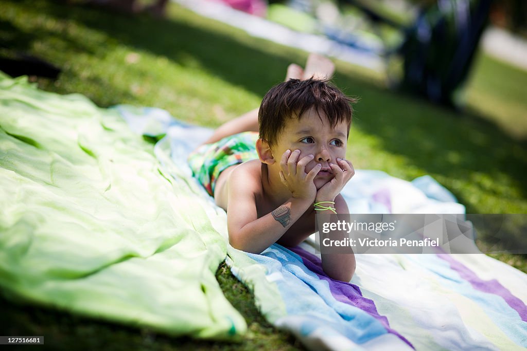 Boy lying on towel with hands on chin