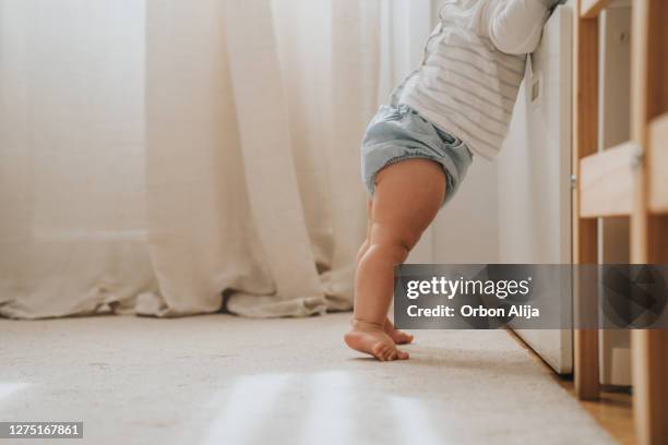 bebé de pie por primera vez - bebé fotografías e imágenes de stock