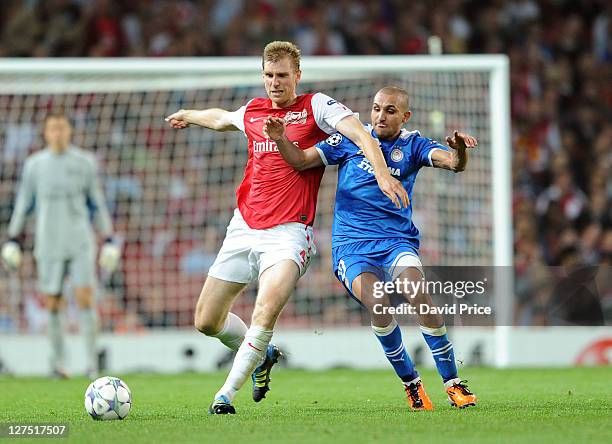 Per Mertesacker of Arsenal holds off Rafik Djebbour of Olympiacos during the UEFA Champions League Group F match between Arsenal FC and Olympiacos FC...