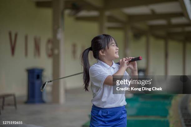 het chinese meisje dat van azië pret en goed heeft om in golfles bij drijfwaaier tijdens regenachtige dag te leren. - drivingrange stockfoto's en -beelden