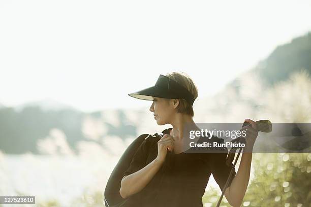 young woman with a golf club near the lake - women golf ストックフォトと画像