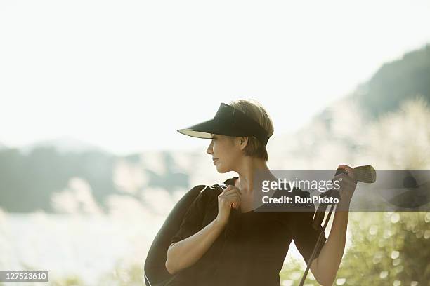 young woman with a golf club near the lake - golf short iron stock pictures, royalty-free photos & images