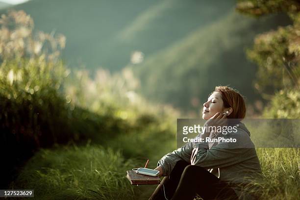 young woman listening to music outside - woman listening to music stock-fotos und bilder