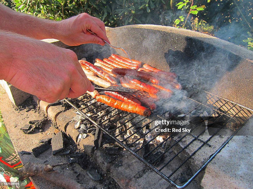 Man turning barbecuing sausages