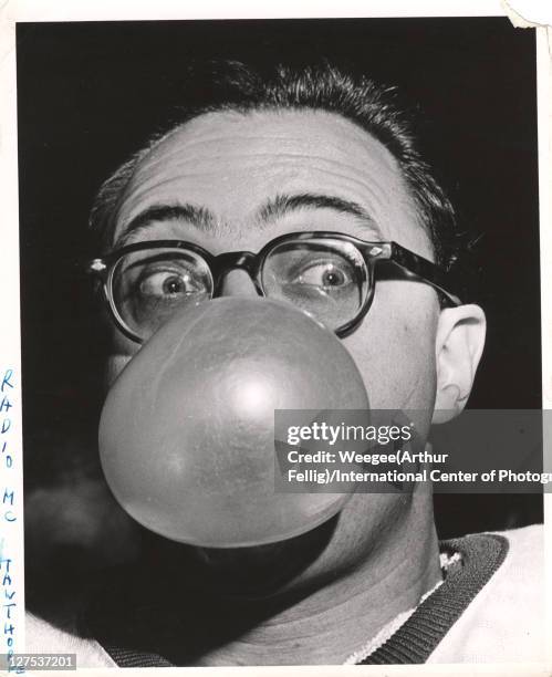 Close-up of American radio host and comedian Jim Hawthorne as he blows a large bubble with chewing gum, his eyes wide open, mid 20th century.