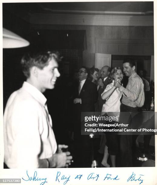 American singer and musician Johnnie Ray smiles as, in the background, singer Vikki Carol dances with disc jockey Art Ford of WNEW Radio at Ford's...