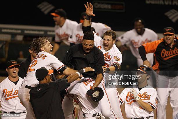 Members of the Baltimore Orioles swarm Nolan Reimold after he scored the winning run to defeat the Boston Red Sox 4-3 at Oriole Park at Camden Yards...