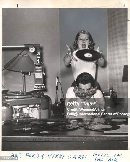 American disc jockey Art Ford of WNEW Radio holds out his hands to catch a record dropped by singer Vikki Carol, New York, New York, mid 1950s.